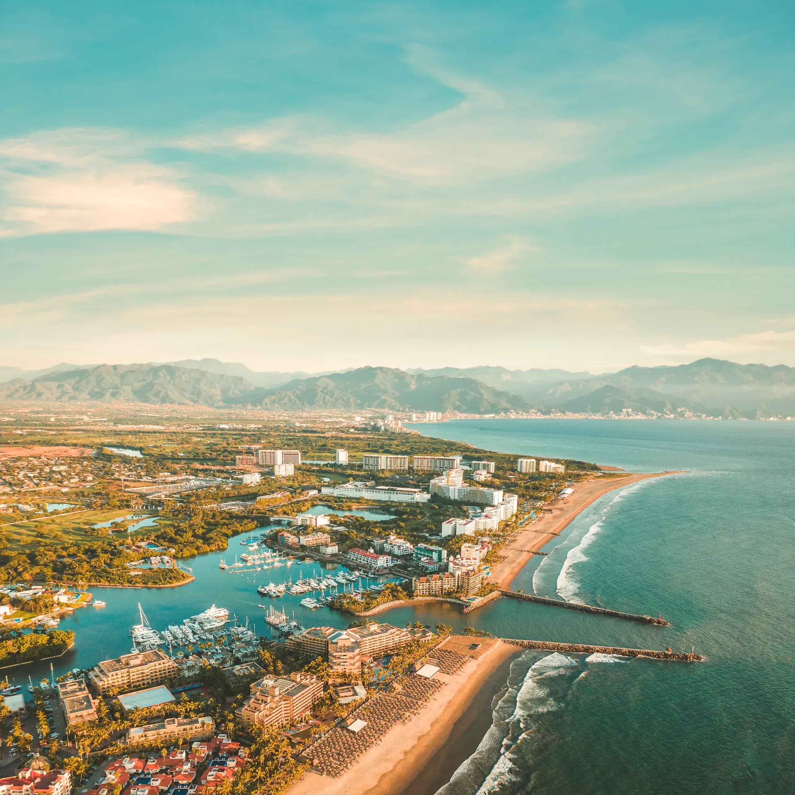 Aerial view of Puerto Vallarta marina, luxury resorts, and beach coastline against mountains